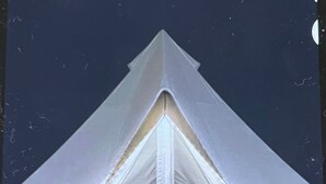 Une tente de forme triangulaire, soutenue par un poteau central.