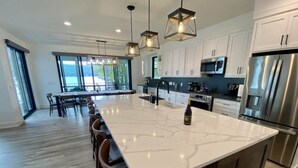 A modern kitchen with a large island, stainless steel appliances, and pendant lighting. - BRAND NEW 7 BR / 5 BA luxury home ON Keuka Lake just outside of Penn Yan! (Penn Yan)