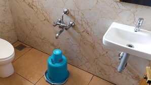 Une salle de bain avec des toilettes, un chauffe-eau bleu et un lavabo avec un robinet.