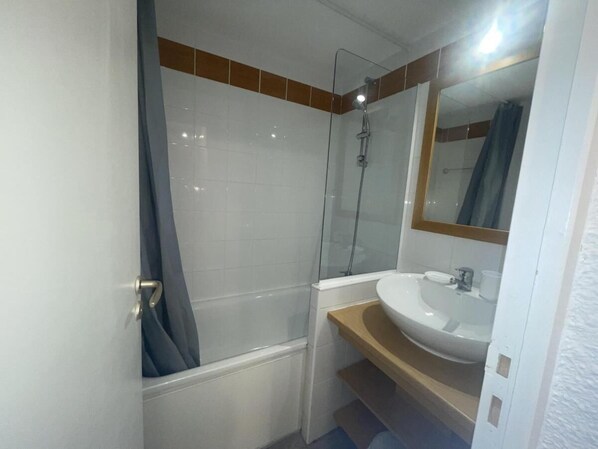 Ein Badezimmer mit einer Duschkabine, einem weißen Waschbecken und einem Spiegel darüber.