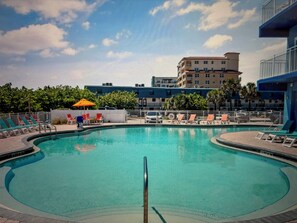 Relax by the oval-shaped pool surrounded by lounge chairs and a low wall.