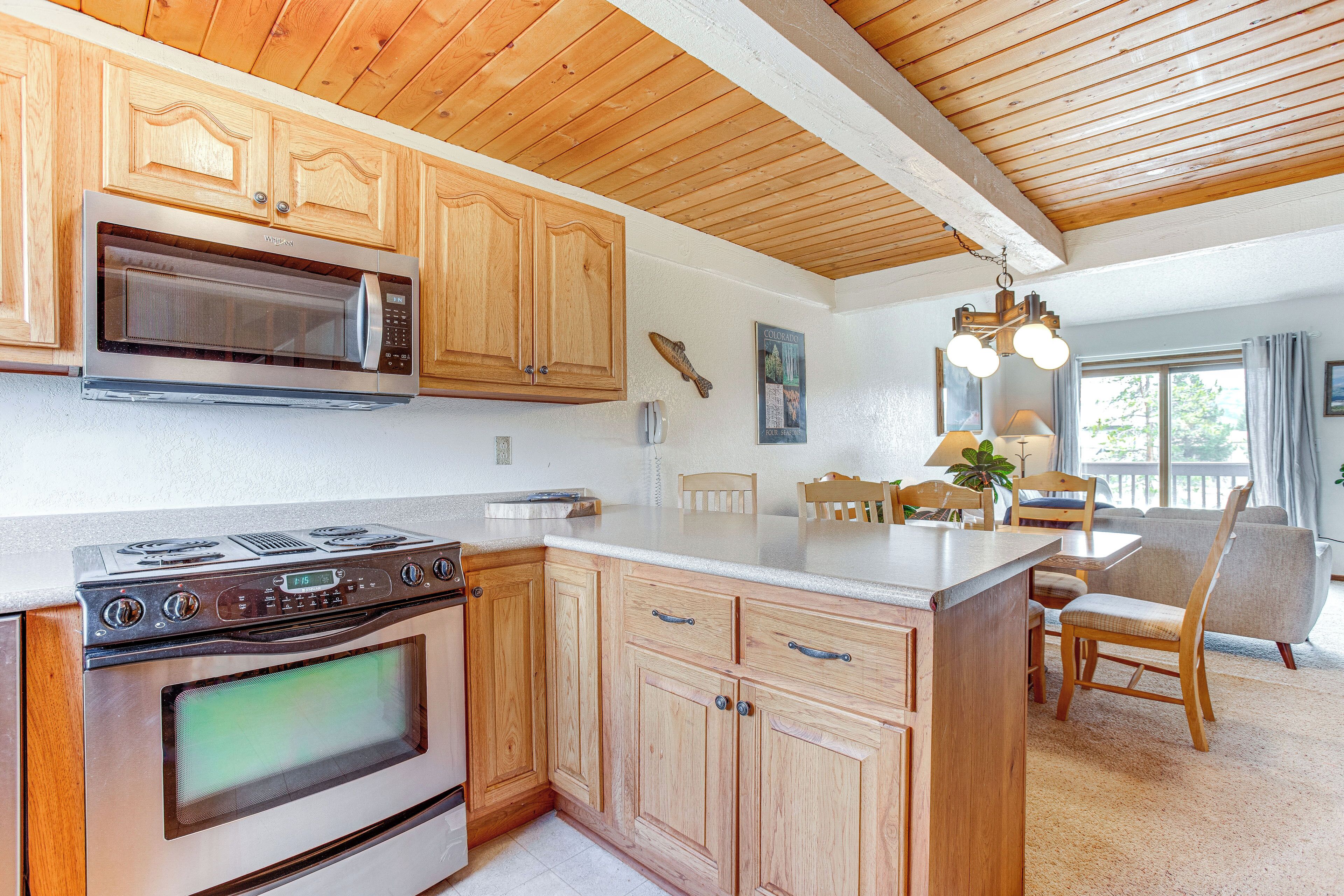 A kitchen with wooden cabinets, a microwave, an oven, and a dining area with a table and chairs.