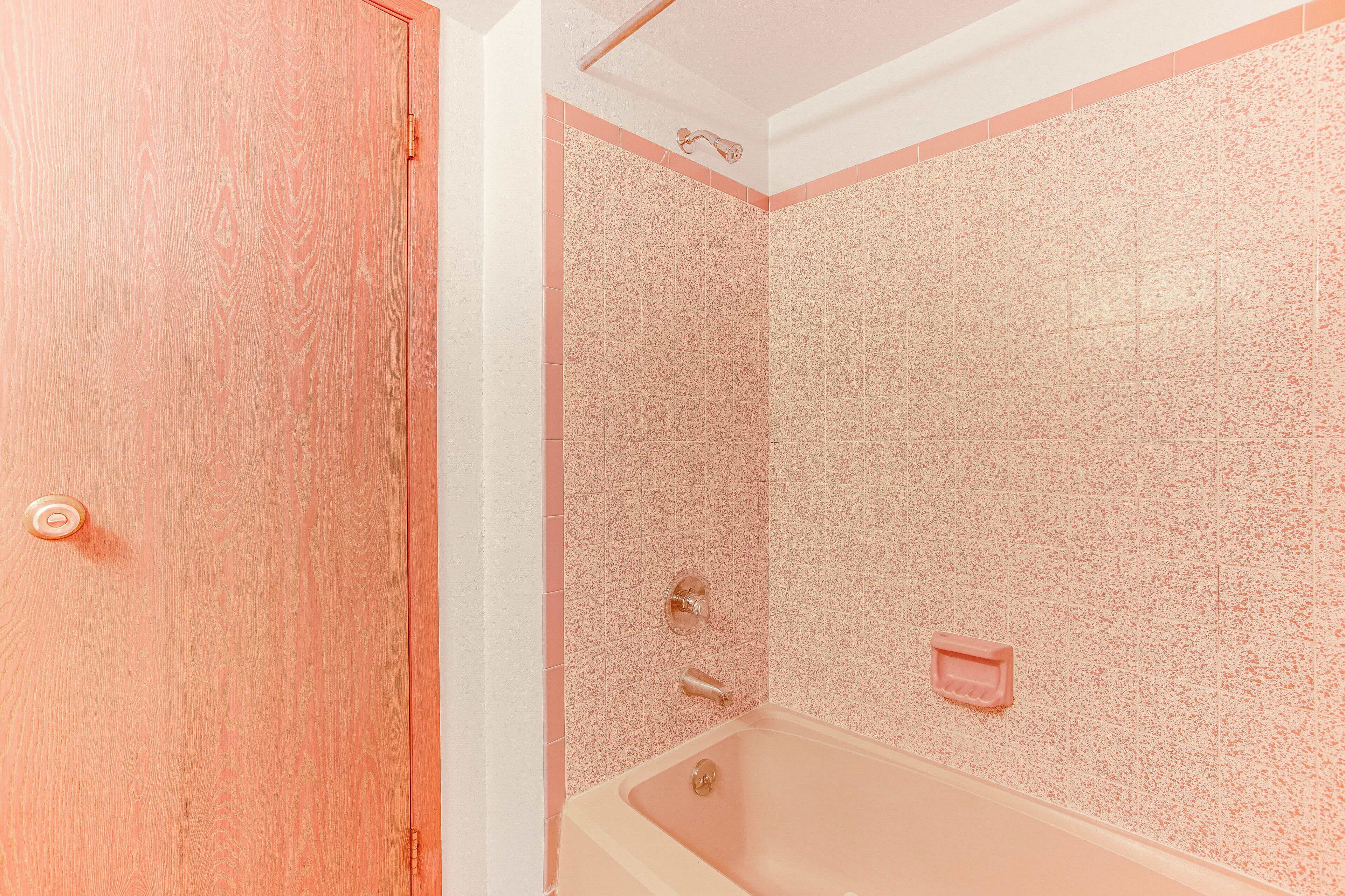 A bathroom with a wooden door, a bathtub, and a shower area.