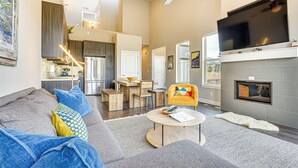 A spacious living area with a sofa, coffee table, and a TV mounted on the wall. - Walk to Dtwn: Fraser Retreat w/ Hot Tub & Views! (Fraser)