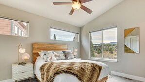 A bedroom with a large bed, a ceiling fan, and two windows offering a view of the outdoors. - Walk to Dtwn: Fraser Retreat w/ Hot Tub & Views! (Fraser)