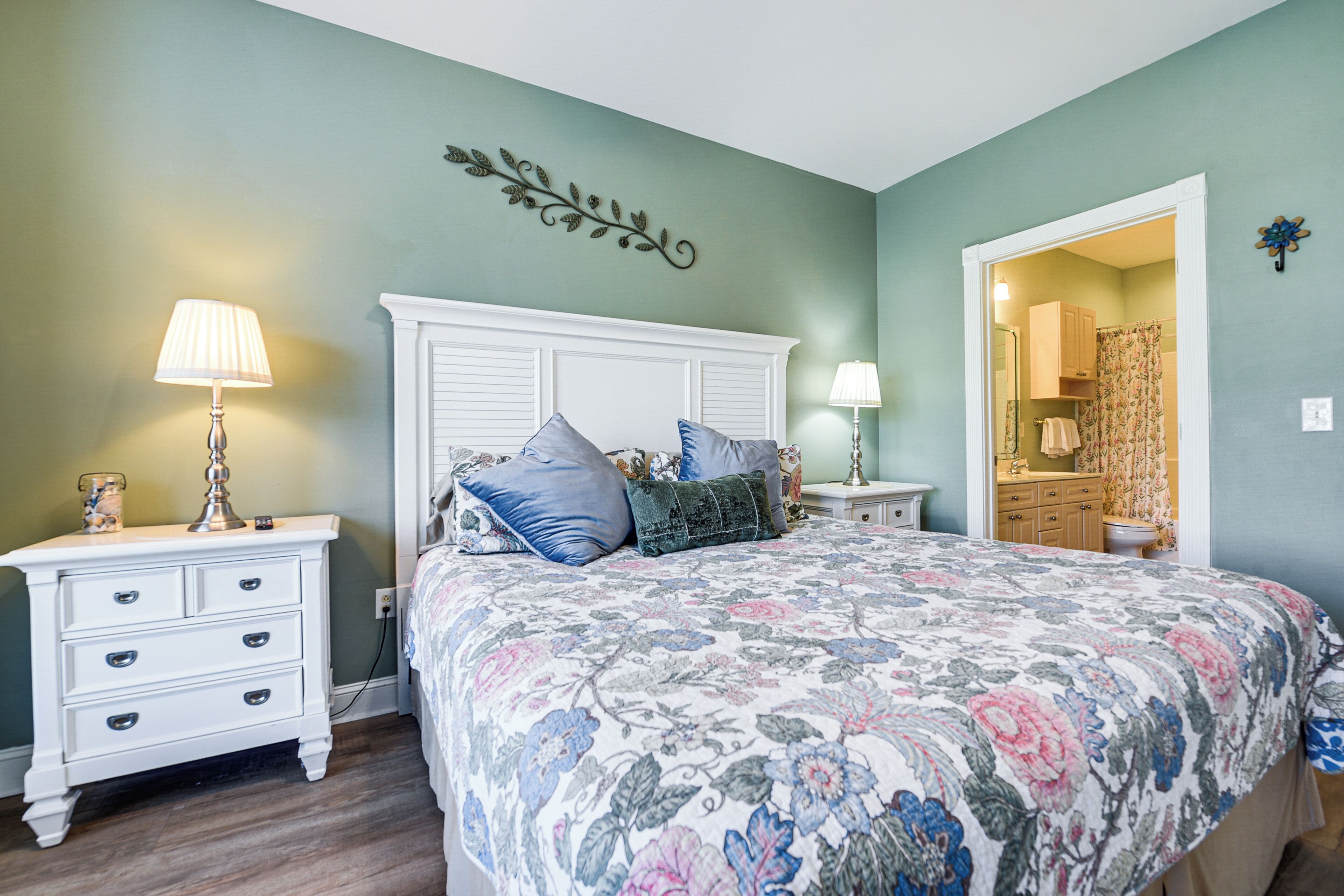 A bedroom with a large bed, two bedside tables, a nightstand, and a dresser.