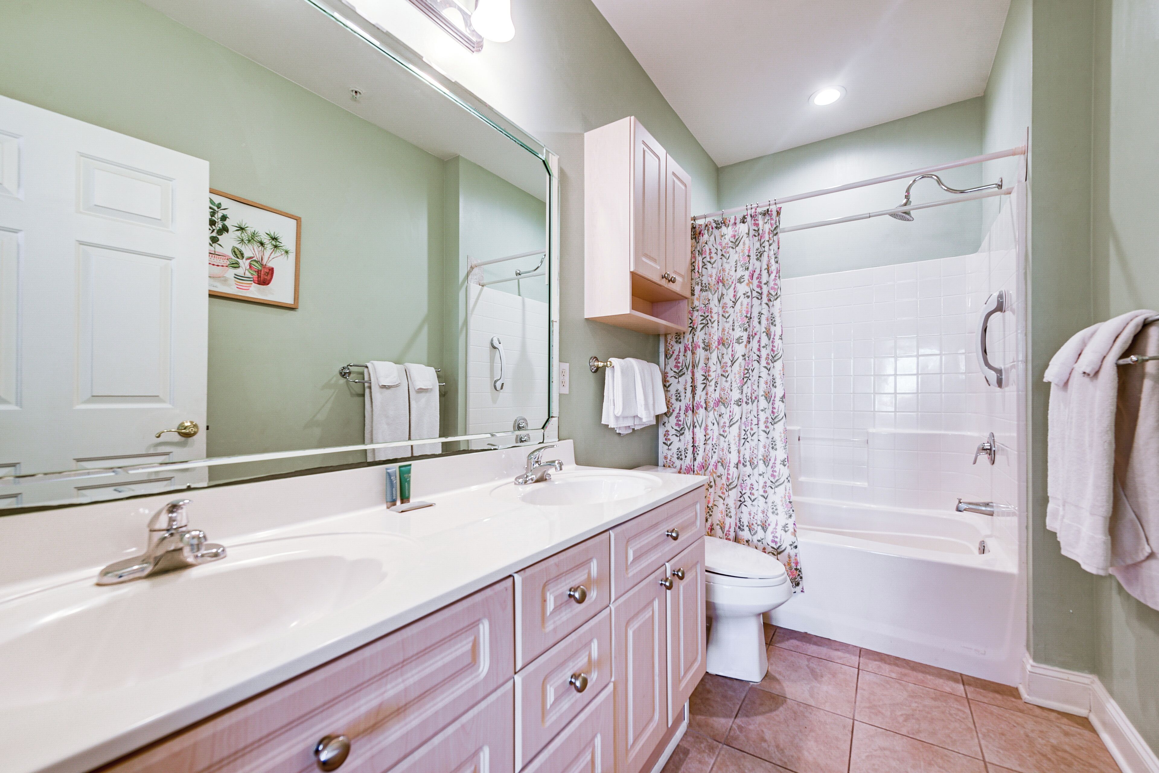 A bathroom with a double sink vanity, a toilet, a bathtub, and a shower curtain.