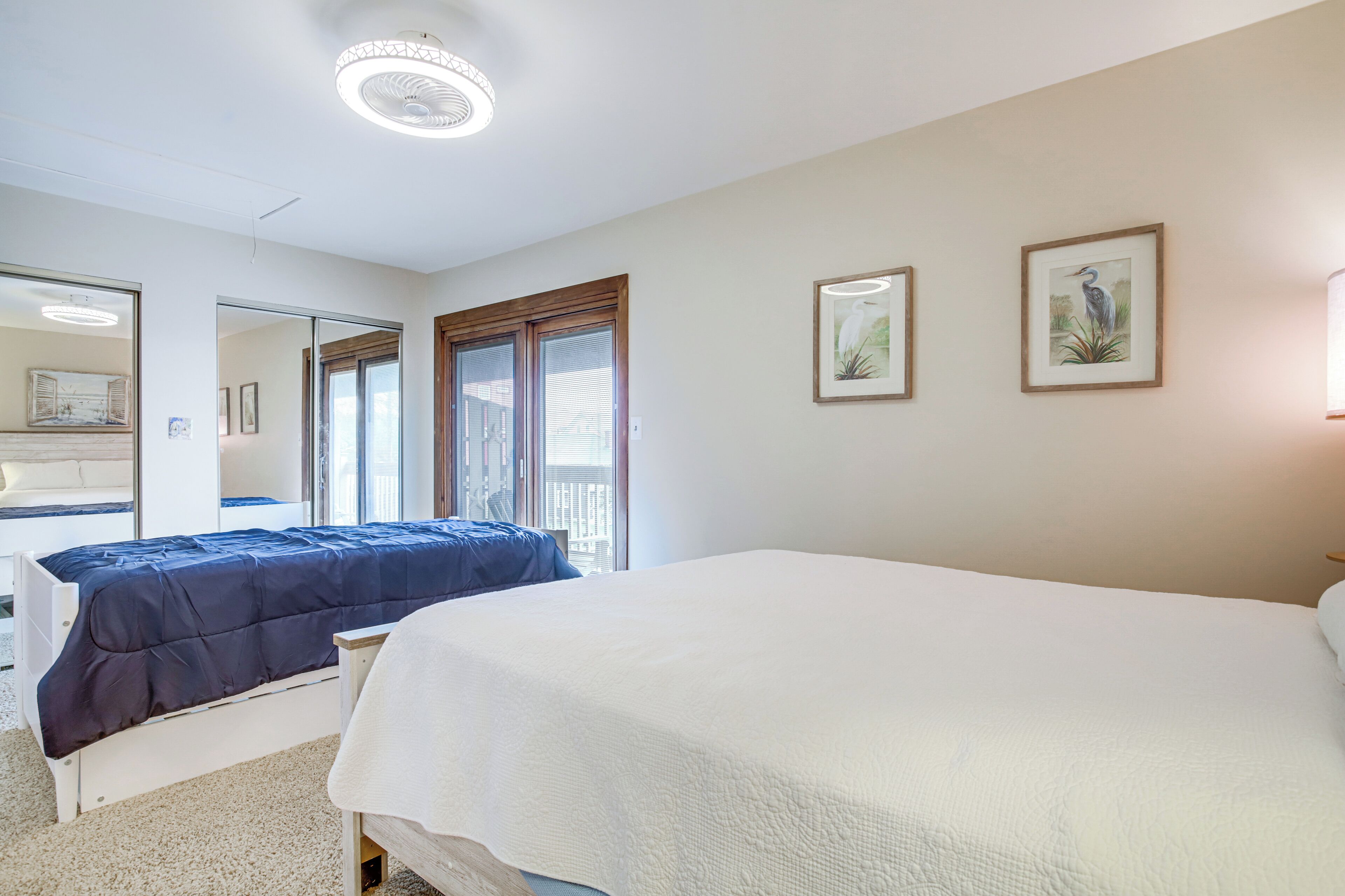 A bedroom with two beds, a large mirror, and framed artwork on the wall.