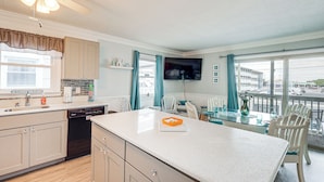 A kitchen with a dishwasher, a large island, and a dining area with chairs and a table.