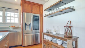 Eine moderne Küche mit Edelstahlgeräten, Holzschränken und einem rustikalen Holztisch mit Gläsern und Geschirr.