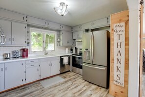 A modern kitchen with white cabinets, stainless steel appliances, and a wooden sign that says "Give Thanks." - Lakefront Home in Hartford: Hot Tub, Kayaks & Dock (Hartford)