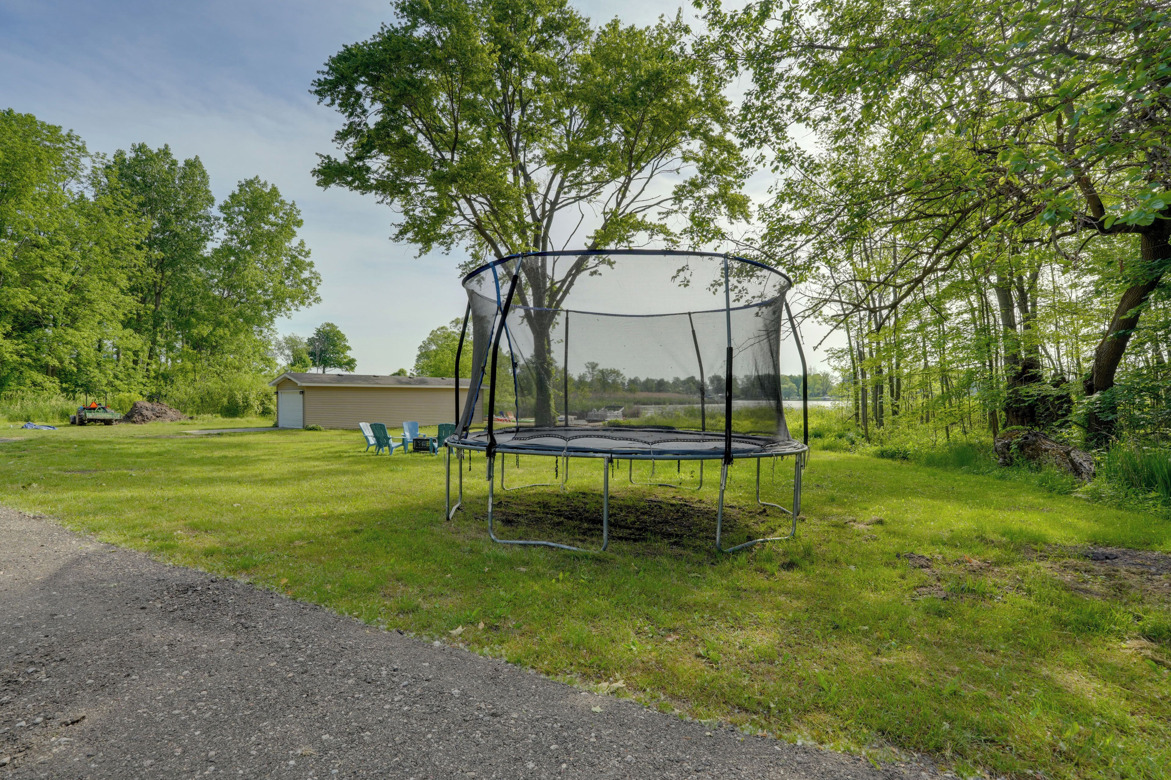 A trampoline in a grassy yard with trees and a shed in the background.