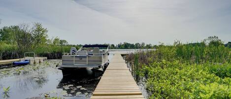 Une jetée en bois s’étendant sur une étendue d’eau, avec un bateau amarré à son extrémité.