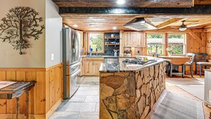 Una cocina amplia con armarios de madera, una isla de piedra y un refrigerador grande.