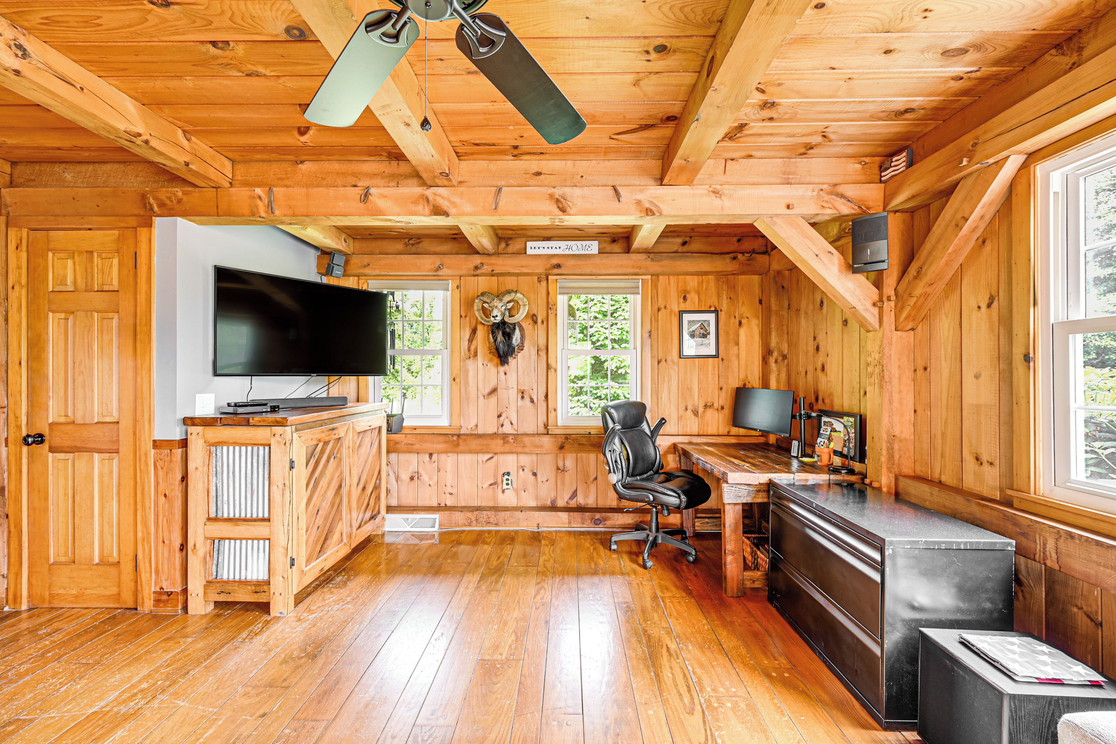 A cabin interior with a wooden interior, a large TV, a desk, and a chair.