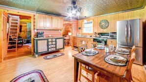 A wooden cabin interior with a dining table set for four, kitchen appliances, and a ladder in the corner. - Cardinal Pines Cabin on 8 Acres - Dog Friendly! (New Berlin)