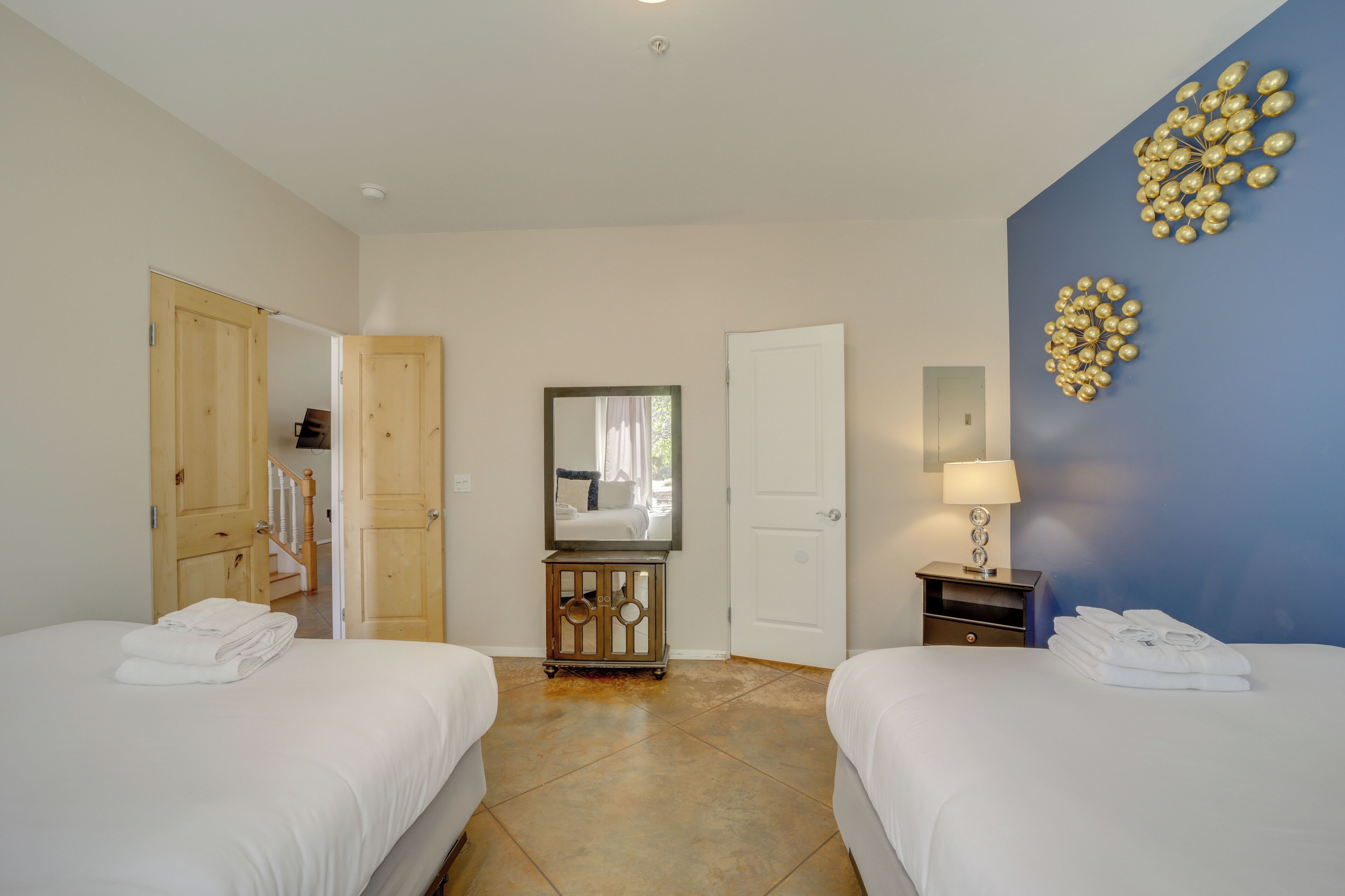 Habitación de hotel con dos camas, un espejo, una puerta, una mesita de noche y un adorno en la pared.