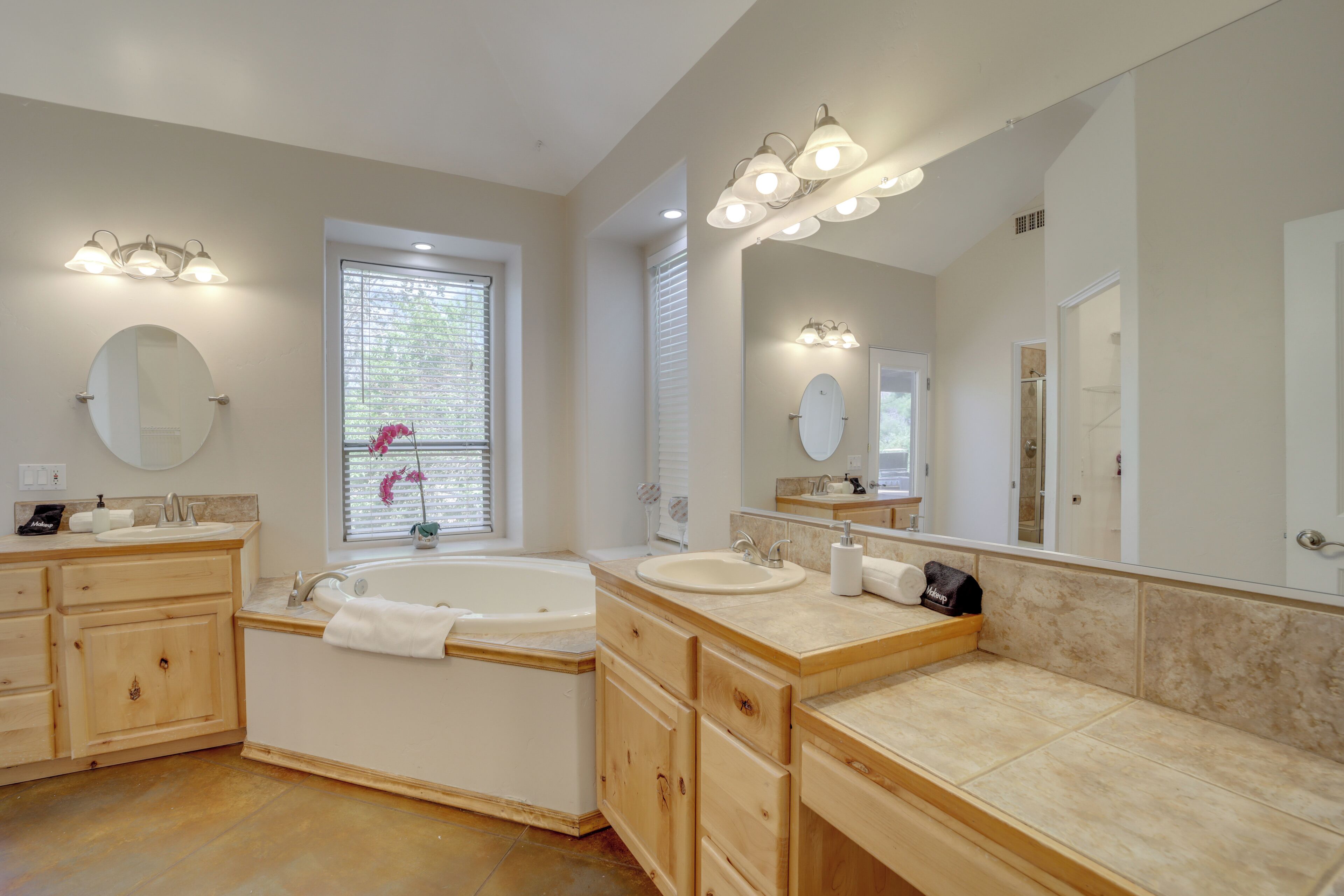 A spacious bathroom with a double sink vanity, a large mirror, and a bathtub.