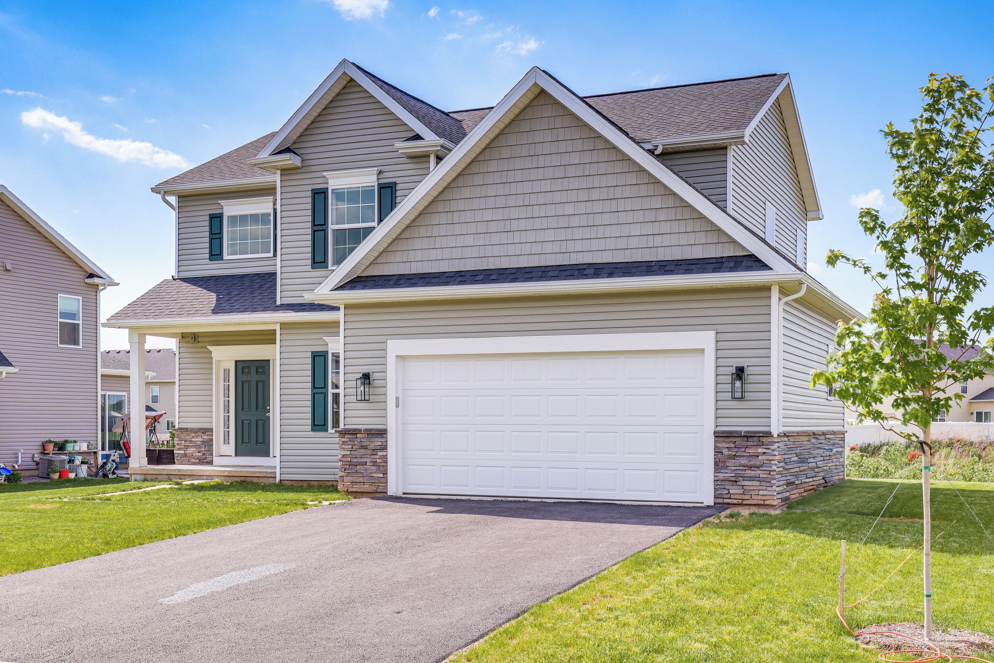 A two-story house with a garage, a front porch, and a well-maintained lawn.