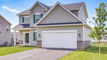 A two-story house with a garage, a front porch, and a well-maintained lawn.