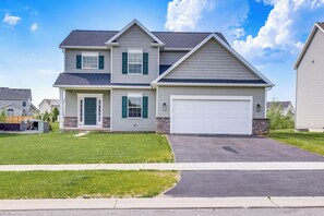 A two-story house with a garage, a well-maintained lawn, and a clear sky.