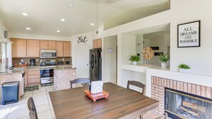A modern kitchen with wooden cabinets, stainless steel appliances, and a dining area with a wooden table and chairs.