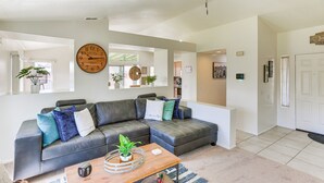 A modern living room with a sectional sofa, a wooden coffee table, and a large wall clock.