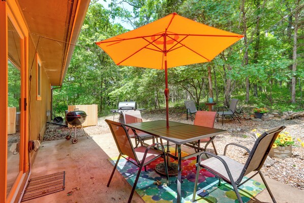 Relax in a serene, setting surrounded by nature, with a shaded patio featuring a table and chairs.