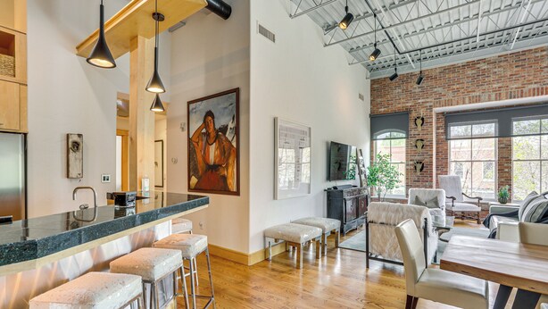 A spacious kitchen with a long island, bar stools, and a dining area with a wooden table and chairs. - Near Trail: Dtwn Eagle Ranch Condo w/ Balcony (Eagle)