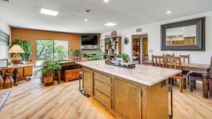 A spacious kitchen with wooden cabinets, a large island, and a dining area with wooden chairs and a table. - Oro Valley Retreat w/ Pool & Breathtaking Views! (Oro Valley)