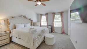 Ein Schlafzimmer mit Bett, Nachttisch, Schminktisch, Kommode und Deckenventilator.