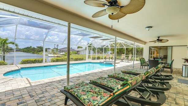 Un espace aménagé au bord de la piscine, avec des chaises longues, une piscine et un patio couvert.