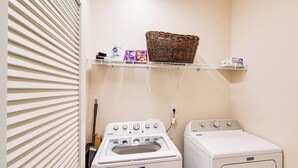 A laundry room with two washing machines, a wicker basket on a shelf, and a hanging rack with laundry supplies. - 16 Mi to Lake Tahoe: Carson City Townhome (Carson City)