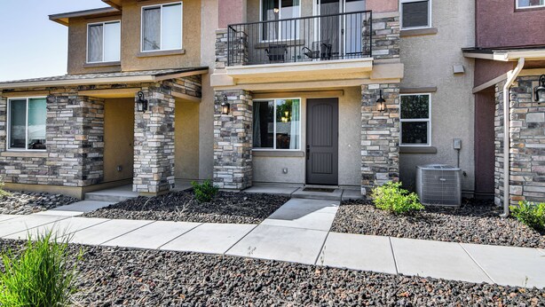 A two-story residential building with a stone facade, a balcony with outdoor furniture, and an air conditioning unit. - 16 Mi to Lake Tahoe: Carson City Townhome (Carson City)