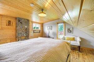 Un dormitorio con una cama grande, techo de madera, pared de piedra y ventana con vistas.