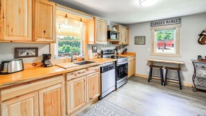 A kitchen with wooden cabinets, a stainless steel toaster, a microwave, and a sink. - Deck & Scenic View: Historic Cabin in Piney Creek! (Piney Creek)