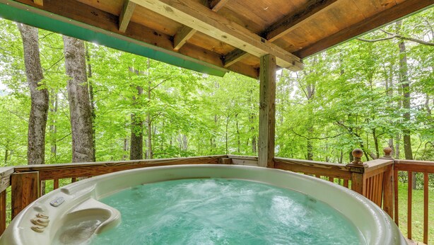 A hot tub with a wooden deck and a view of a forest. - Serene Maggie Valley Retreat w/ Deck & Hot Tub! (Maggie Valley)