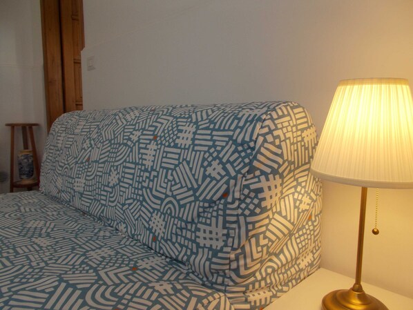 Un canapé à motifs dans une pièce où se trouve une lampe.