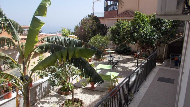 Ein Balkon mit Blumentöpfen, einem Tisch und Stühlen.