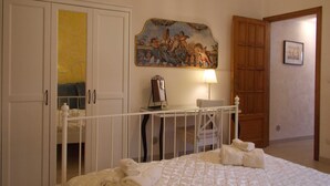 Ein Hotelzimmer mit Bett, Schreibtisch mit Lampe, einem Bild an der Wand und einer Tür.