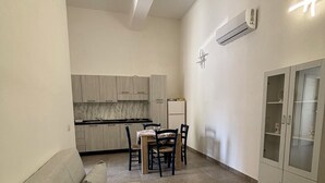 Un espacio habitable compacto con sofá, mesa de comedor, sillas, zona de cocina y un mueble.