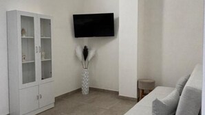 Una sala de estar moderna con un mueble blanco, un televisor de pantalla plana montado en la pared y un sofá gris.