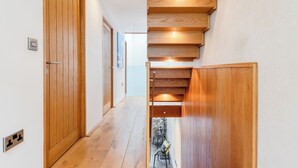A wooden staircase with a modern design, leading to an upper floor. - Architecturally designed fishing warehouse conversion (Newlyn)