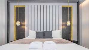 Moderni hotellihuone, jossa on suuri sänky, kaksi yöpöytää, pystysuorilla linjoilla koristeltu sängynpääty ja kaksi riippuvalaisinta.