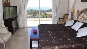 A bedroom with a bed, a TV, a dresser, and a view of the ocean. - Marbella Coast Hotel (Marbella)