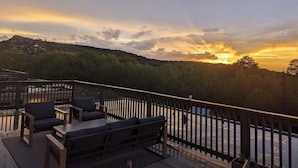 Eine Terrasse mit Gartenmöbeln mit Blick auf einen Sonnenuntergang.