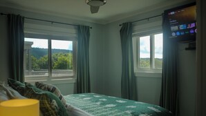 Ein Schlafzimmer mit Bett, Vorhängen, einem Fenster und einem Fernseher.