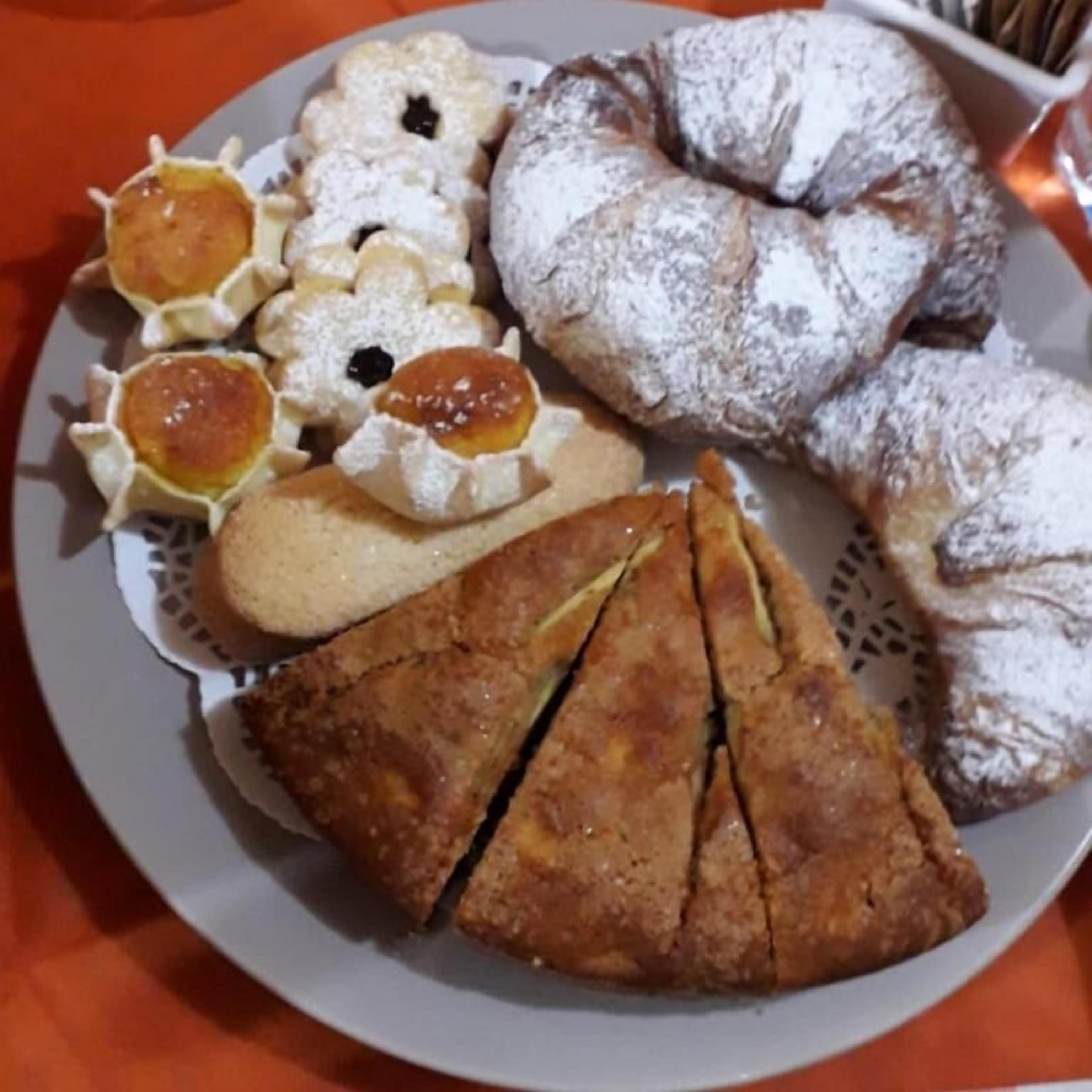 En tallerken med et udvalg af kager og bagværk, blandt andet croissanter, et stykke kage og små tærter.