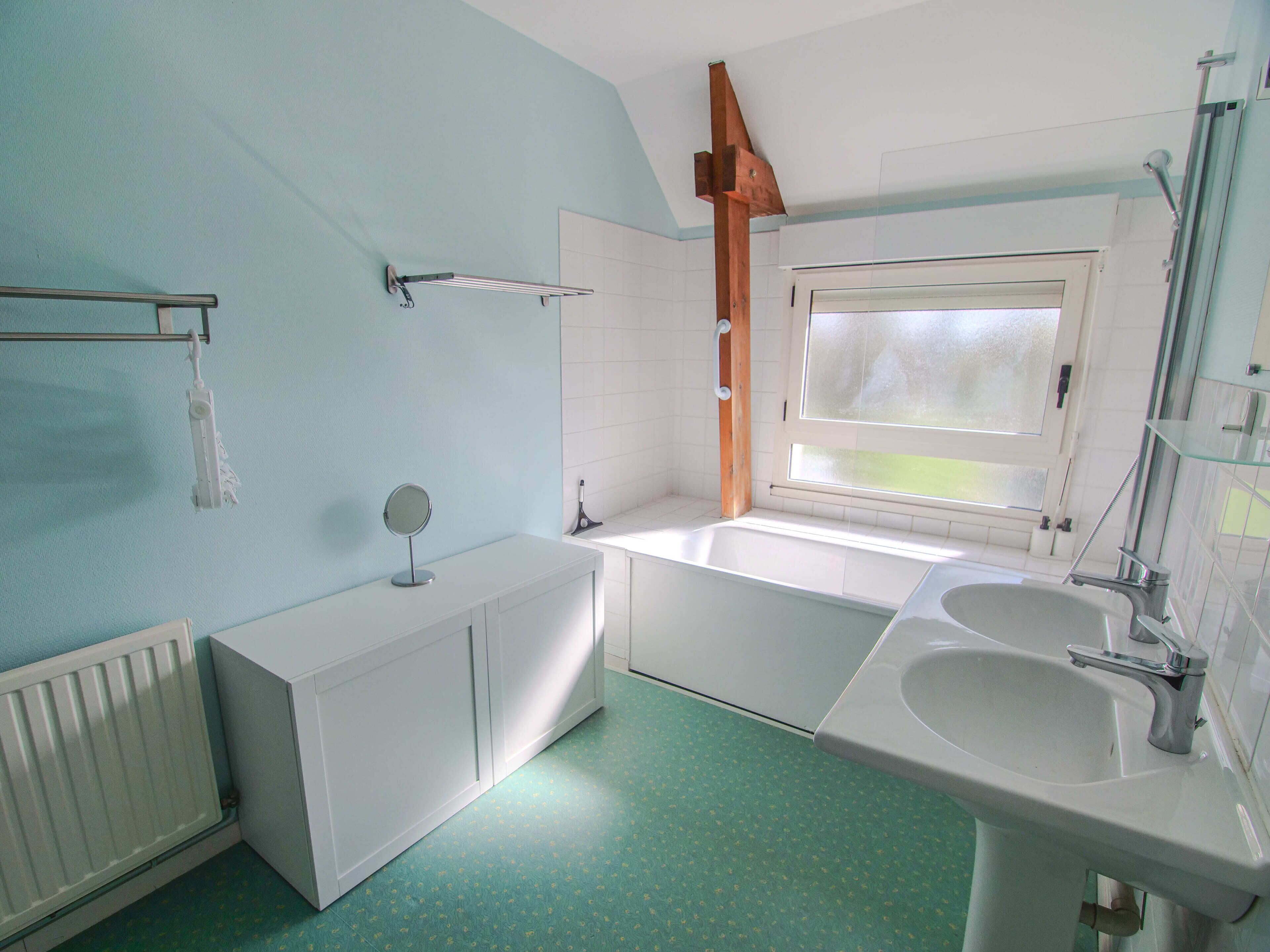 Un baño con bañera, lavamanos, espejo y ventana.