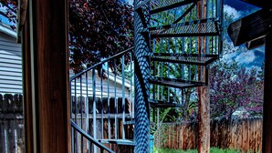 Una escalera de caracol conduce a un nivel superior, rodeada de vigas de madera y una barandilla de metal.